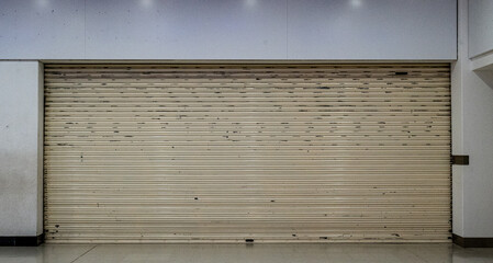 A shop that has closed down and is shuttered up in a shopping mall depicting the downturn in the British economy.