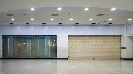 A shop that has closed down and is shuttered up in a shopping mall depicting the downturn in the British economy.