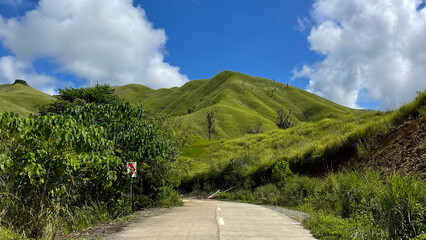 Scenic Green Hills and Winding Road Under Blue Sky – Tropical Landscape