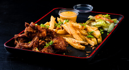 American fast food - chicken wings, French fries and salad with sauce