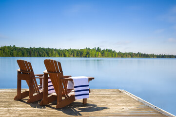 A calm lake with a wooden dock in the foreground in Algonquin Provincial Park, Ontario, Canada. Two...