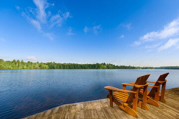 A calm lake with a wooden dock in the foreground in Algonquin Provincial Park, Ontario, Canada. Two...