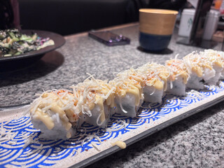 sushi roll with delicious cheese toppings ready to be enjoyed at the restaurant table. sushi lovers