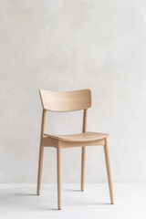 Fototapeta premium close-up of single wooden dining chair against white-washed wall natural light highlighting grain