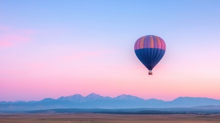 single hot air balloon drifts serenely at dawn its vibrant colors contrasting pastel morning sky over open plain mountains