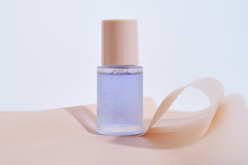 A bottle of blue serum on a delicate beige background.