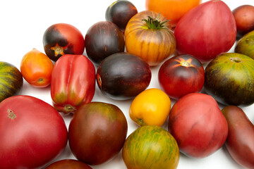 Colorful raw tomatoes: red, yellow, orange, green on a white background. Ripe, juicy, different colors and shapes. Close-up side view