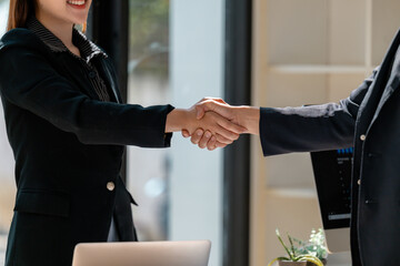Businesswomen shaking hands, closing a deal in the office