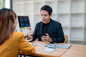 Businessman explaining financial charts to colleague during a meeting in a modern office