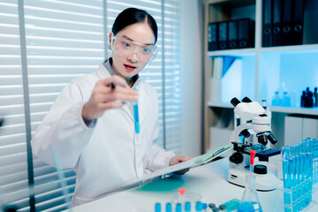 Woman in a lab coat holding a test tube with a blue liquid in it