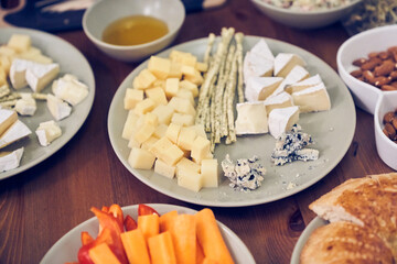An appetizer of different types of diced cheese is on the plate. Honey with nuts on a table with space to copy. High quality photo