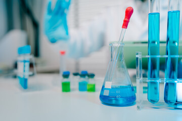 Lab table with a blue beaker and a red dropper