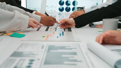 A diverse team of professionals engages in a collaborative meeting, analyzing financial reports and data charts in a modern office space, fostering innovative solutions. SACTR