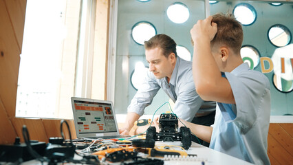 Caucasian teacher help student fixing car model and giving advise for programing system or coding...