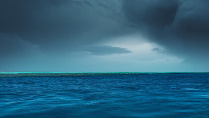 Fototapeta premium A stunning seascape featuring deep blue ocean waters under a dramatic stormy sky, capturing the beauty of nature’s raw power