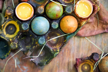 colorful Easter eggs painted with natural dyes lying in a palette on a wooden table, dark background, top view