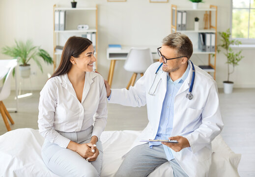 Happy female patient consults with a doctor or nurse during a visit to the hospital or clinic. The healthcare provider focuses on the patient care, ensuring her medical needs are met.