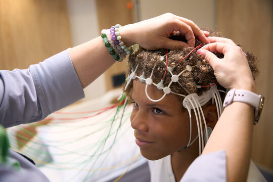 Close-up of diagnostician positioning multiple electrodes on young patients scalp
