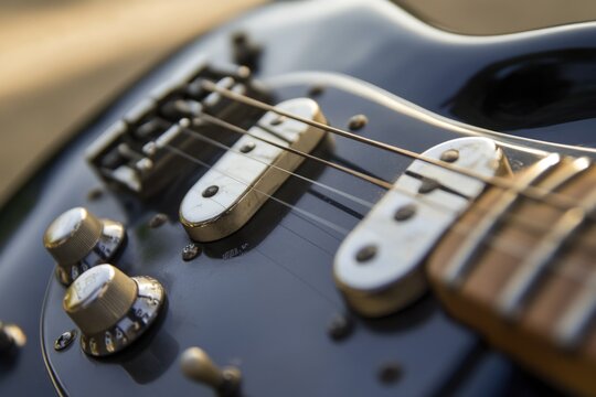 A close-up shot of an electric guitar's body and strings - Powered by Adobe