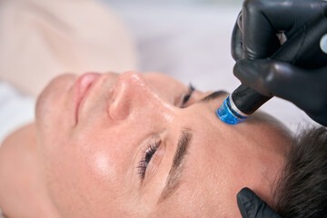 Close-up view man visiting cosmetologist, doing hydrafacial procedure