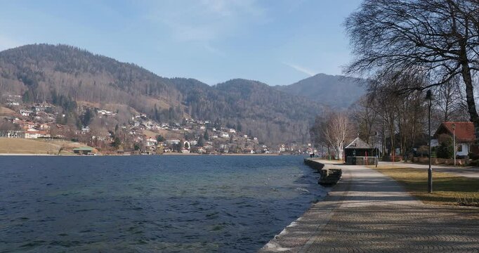 Beautiful lakeside promenade of Tegernsee along the southern shore with views of the wooded hills surrounding the town of Tegernsee
