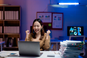 Excited businesswoman celebrating success while working late at night in office