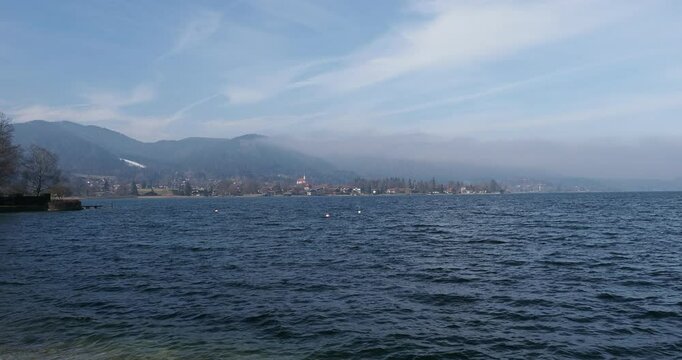 Lake Tegernsee with the town of Bad Wiessee and its chapel facing the island of Ringsee along the western shore at the foot of Bavarian wooded mountains