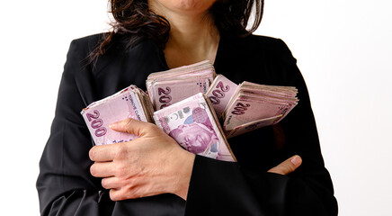 Woman clutches stacks of 200 TL bills in a black jacket. 