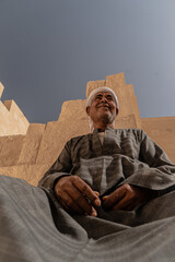 Photo of an Arab man wearing a white turban and traditional clothing with traditional patterns, smiling as he poses for the photo. Travel to Egypt. Valley of the Kings