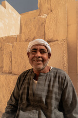 Photo of an Arab man wearing a white turban and traditional clothing with traditional patterns, smiling as he poses for the photo. Travel to Egypt. Valley of the Kings