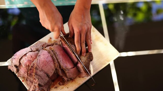 Cook cuts the roast beef into thin slices on a cutting board and stacks it. High quality 4k footage
