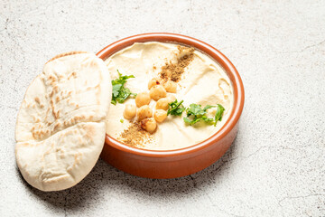 Delicious hummus decorated with chickpeas, parsley and paprika served with pita bread