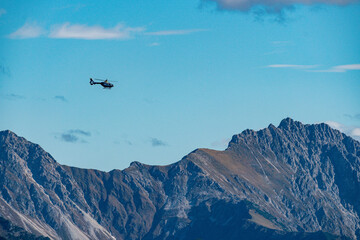 Fototapeta premium Helicopter soaring over majestic alpine peaks during vivid autumn skies in bavaria germany