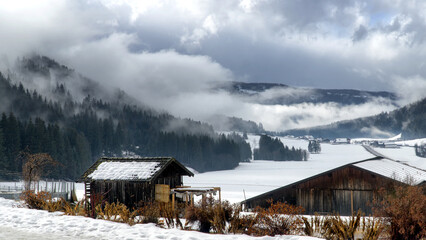Winter mountain valley landscape in mist. Thick fog or clouds covers the valley at dusk. South Tyrol, Alps, Italy, Europe