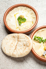 Hummus and baba ghanoush with pita bread and olive oil on gray background
