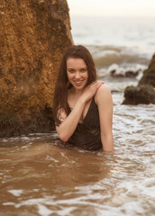 close-up of a slender girl in the sea among the waves.