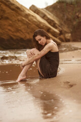 brunette girl is sitting on a sandy beach