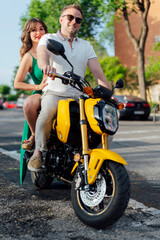 Fototapeta premium Couple riding yellow motorbike in urban setting