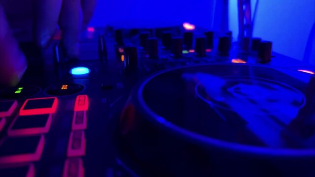 Close-up, DJ hands control DJ mixer at a party, DJ remote control, color and light music.The concept of djing and music