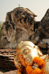 The reclining buddha statues of the Wat Lokaya Sutha Temple, the small golden one in the front, with orange flowers around its neck, the big one in the back, Ayutthaya Historical Park, Thailand