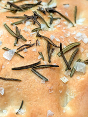 Close up of fresh focaccia bread with salt and rosemary top view just baked