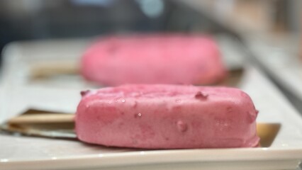 Experience the delightful taste of pink ice cream bars that are expertly crafted and elegantly served on wooden sticks