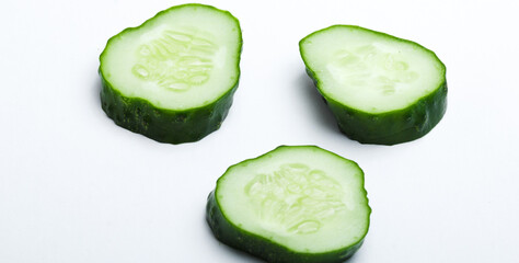 Sliced fresh green cucumber on a white background, showcasing its vibrant color and crisp texture