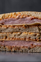 Classic grilled ham and cheese sandwich with golden toasted bread, stacked neatly on a rustic stone surface