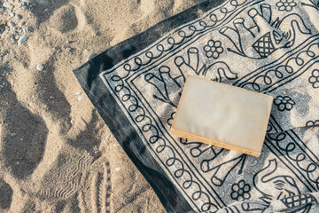 Old book lying on a beach towel on the sand