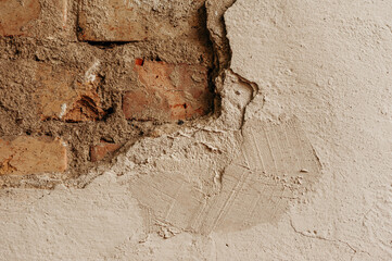 The image shows the process of plastering a wall. The photo shows a hand holding a trowel and applying the mixture to the brick surface.