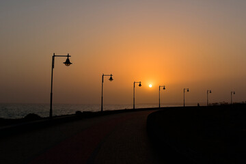 Street light silhouettes in a row at playa honda beach promenade at sunset, lanzarote, canary islands., spain. travel europe.