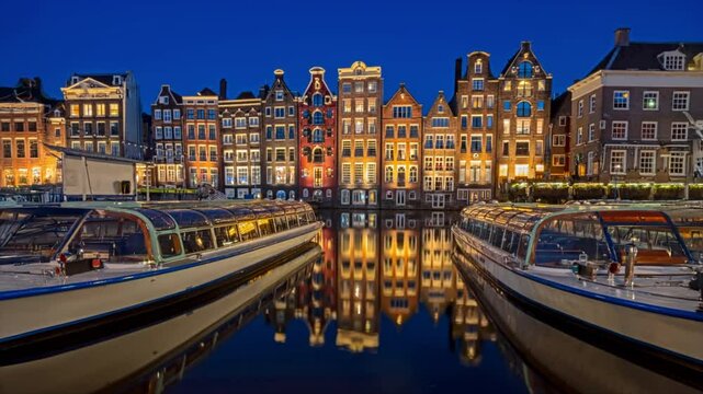 Houses and boats on the Damrak in Amsterdam the Netherlands at sunset
