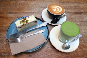 pistachio cake on a plate with a cup of coffee and matcha latte