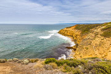 Rugged cliffs rise above tranquil waves, revealing a secluded beach in Port Campbell National Park at the Great Ocean Road.